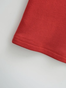 Nahaufnahme des roten Strickkleid-Saums mit professioneller Doppel-Flachnaht-Detail