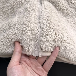 Detailed macro view of soft cream polar fleece texture and sturdy nylon zipper closure