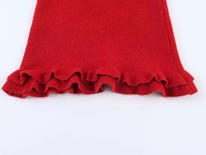 Detail shot of the red knitted fabric texture with elegant ruffle edges on the sleeve
