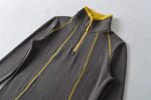 Detailed view of dark grey thermal top with bright yellow zipper and trim accents