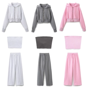 Flat lay of gray and pink 3-piece sporty set with hoodie, crop top, and joggers