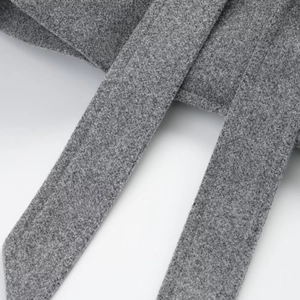 Macro detail of the grey wool blend fabric and premium stitching on the coat belt