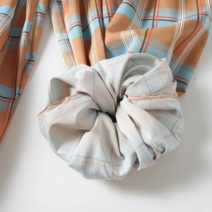 Detail shot of brown and blue plaid scrunchie with focus on stitching and soft texture
