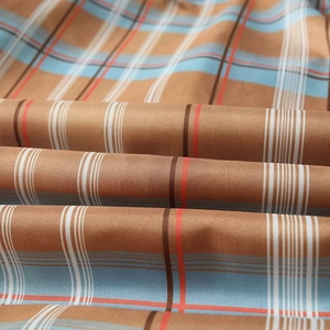 Detailed macro view of plaid fabric featuring a warm brown and sky blue twill weave pattern