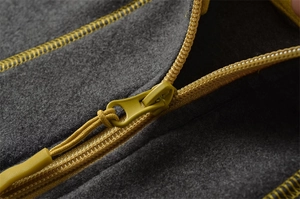 Close-up of contrast mustard yellow zipper and stitching on grey thermal fleece top