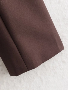 Close-up of deep brown twill wool blend fabric showing fine texture on suit cuff