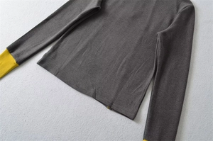 Detail of gray thermal top showing mustard yellow contrast stitching on knit cuffs