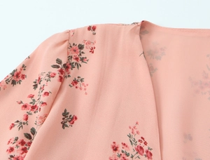 Close-up of lightweight floral chiffon dress with pink base and red flower patterns