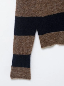 Détail du tissu tricoté à rayures marron et noires avec texture douce et ourlet fendu
