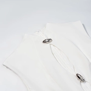 Detail of white high-neck dress with stylish cut-out design and crystal metal buttons