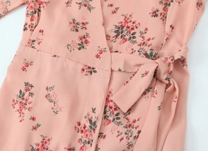Detail of V-neck wrap dress with pink floral print and a delicate waist tie bow