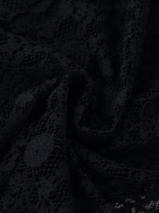 Macro shot of intricate black floral lace fabric with delicate mesh texture and patterns