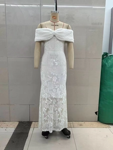 Détail d'une robe en dentelle blanche avec col en fausse fourrure et broderies florales