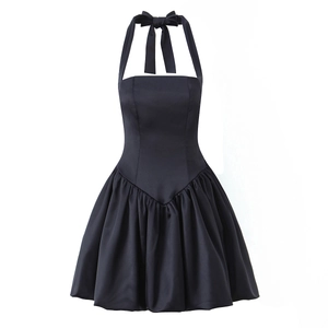 Detail of elegant black halter dress featuring a large bow tie and pleated satin skirt