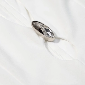 Macro view of silver marquise crystal button on textured white knit dress fabric