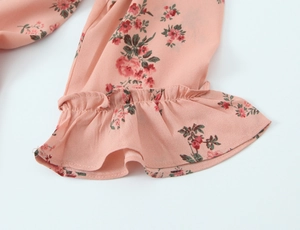 Close-up of floral chiffon dress cuff with ruffle edges and delicate pink pattern