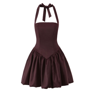 Macro detail of the pleated puff hem and V-shaped waistline on a burgundy halter dress