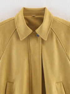 Detailed close-up of mustard yellow suede texture and silver metal button on bomber jacket