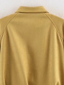 Detail view of mustard yellow suede flight jacket showing back seams and shoulder texture