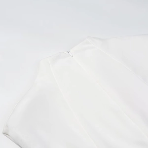 Detail view of the seamless invisible zipper closure on back of white sleeveless dress