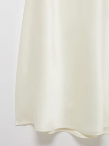 Vue macro de l'ourlet d'une robe en satin blanc avec une texture de tissu de qualité