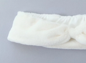 Détail d'un bandeau en peluche blanche avec un nœud torsadé élégant et doux
