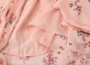 Detailed close-up of pink floral chiffon fabric with soft red flowers and light texture
