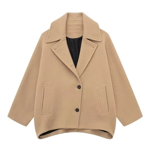 Detail of camel wool coat featuring notched lapels, two buttons, and textured fabric