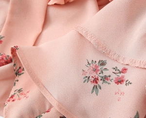 Close-up of floral print fabric detail with neat stitching and pink chiffon texture