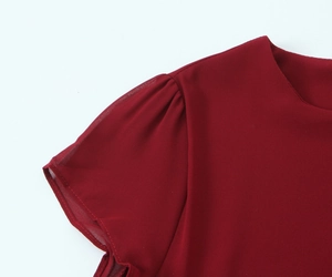 Dettaglio dell'abito rosso vino con scollo rotondo ed eleganti maniche a sbuffo