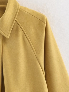 Detailed view of mustard yellow suede bomber jacket showing raglan sleeve seams
