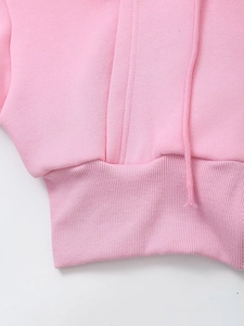 Detail of pink hoodie featuring elastic ribbed hem and matching flat drawstrings