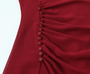 Dettaglio in chiffon plissettato rosso scuro con bottoni decorativi in tessuto coordinati