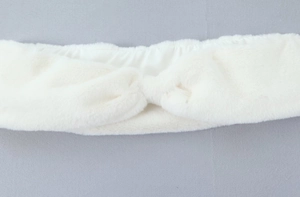 Détail d'un bandeau en fausse fourrure blanche douce avec un design de nœud torsadé