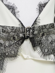 Vue détaillée d'un corsage en satin blanc avec dentelle noire et boucle en métal argenté