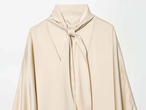 Détail de la blouse en satin champagne avec col lavallière et texture soyeuse