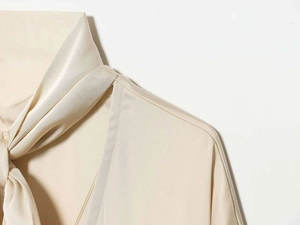 Détail de la robe en satin champagne montrant le col noué et la texture soyeuse du tissu