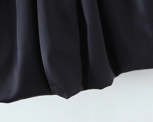 Detail view of the high-quality black woven fabric texture on a backless mini dress