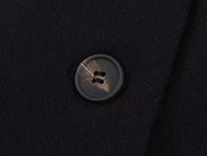 Macro detail of the amber-textured button on the black winter wool coat fabric