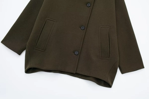 Detail of dark olive wool coat featuring large decorative pockets and black buttons