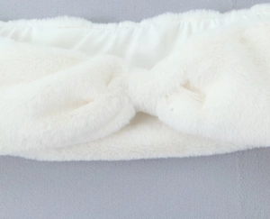 Gros plan d'un bandeau en fausse fourrure blanche avec un nœud torsadé et une texture douce