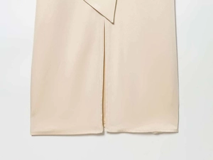 Vue détaillée de la robe en soie beige avec une fente centrale chic et un ourlet superposé