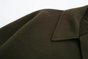 Macro shot of dark olive green wool blend coat featuring notched lapels and twill texture