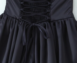 Macro shot of back criss-cross lacing and smocked elastic detail on black satin dress