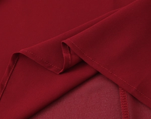 Dettaglio della trama in chiffon bordeaux con cuciture pulite sull'abito con spacco