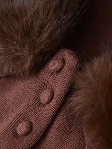 Detailed macro view of dark brown knit fabric with faux fur collar and textured buttons