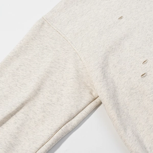 Detail view of distressed shoulder seams and frayed cutouts on a gray hoodie fabric