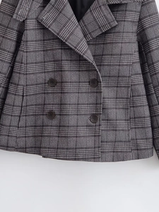 Detailed close-up of retro plaid pattern fabric and double-breasted buttons on jacket