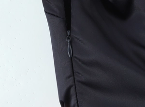 Close-up of invisible zipper detail on black backless halter dress with smooth fabric