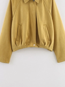 Detail of mustard yellow faux suede bomber jacket with side pockets and metal snap buttons